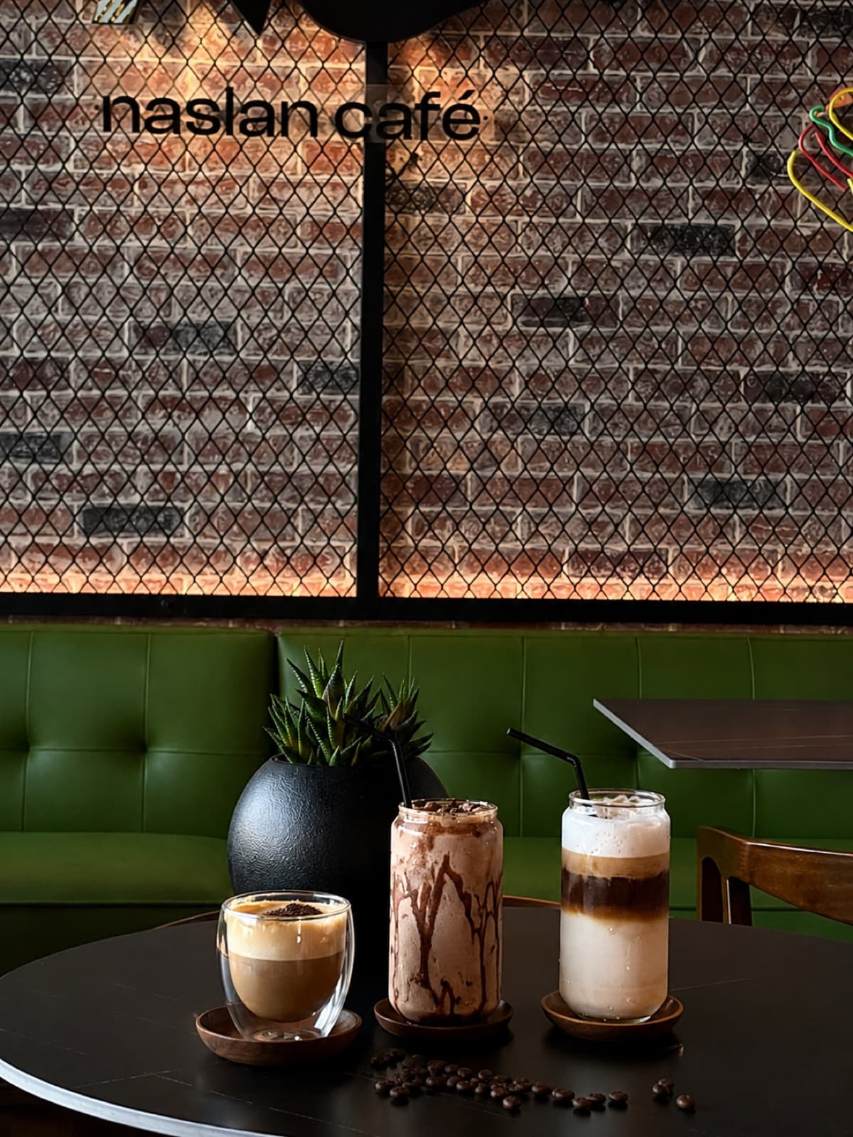 Naslan Café interior with three coffees on a table by the brick wall