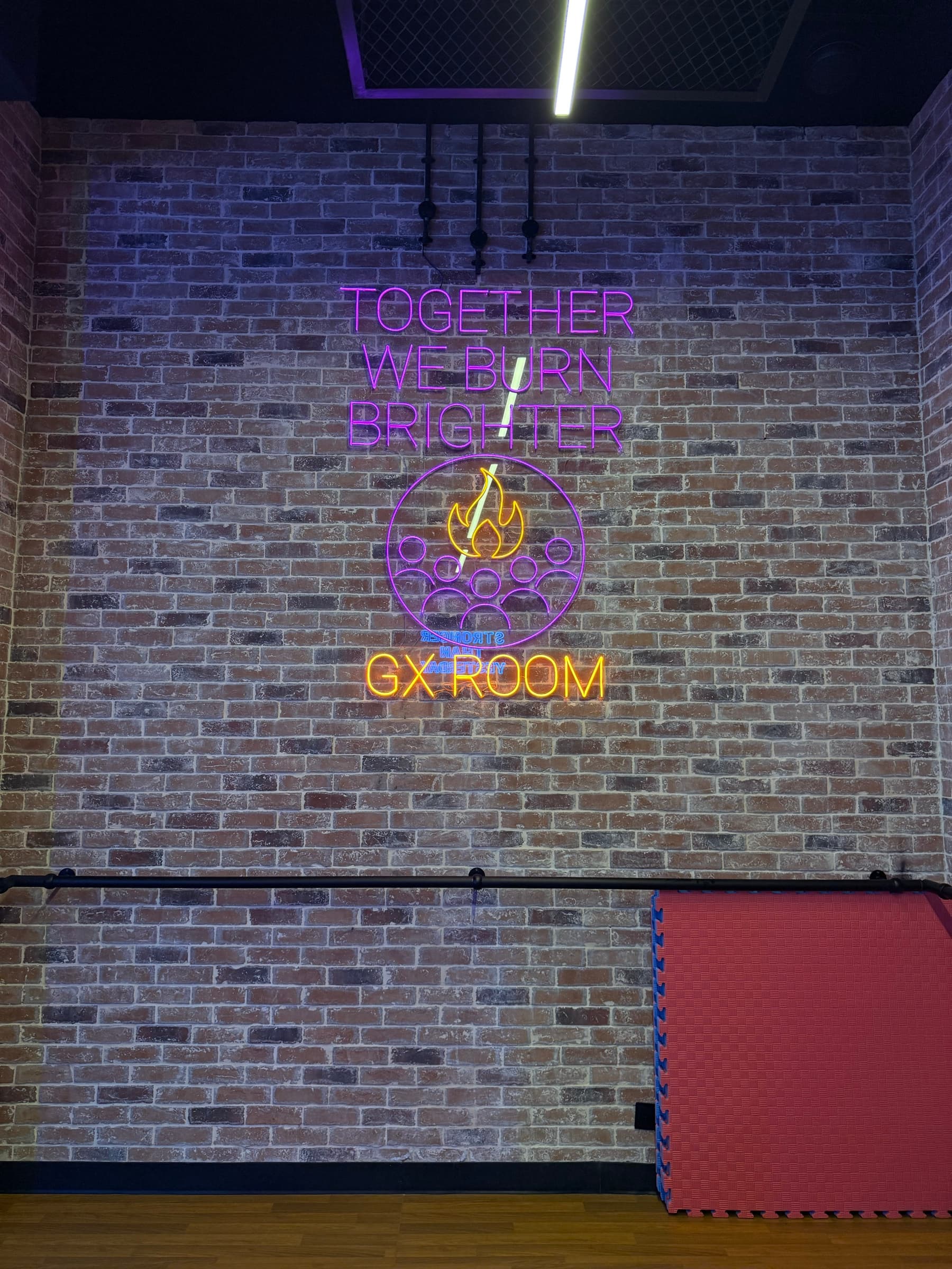 Cardio Zone training wall with a neon Together We Burn Brighter sign