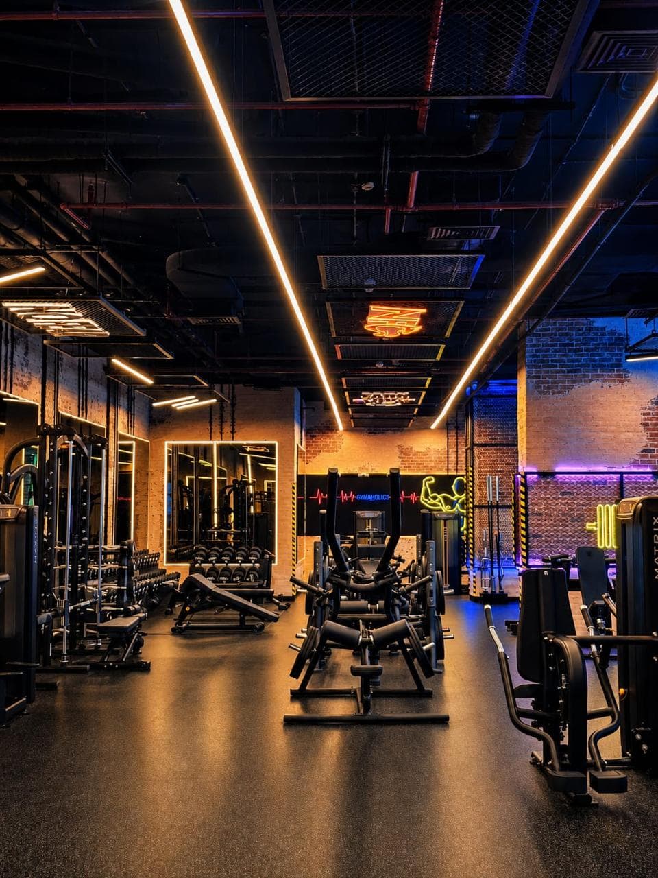Main gym floor with strength machines and warm architectural lighting