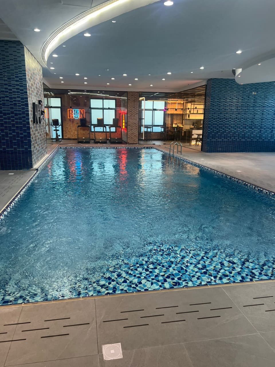 Indoor lap pool with the gym floor visible behind glass walls